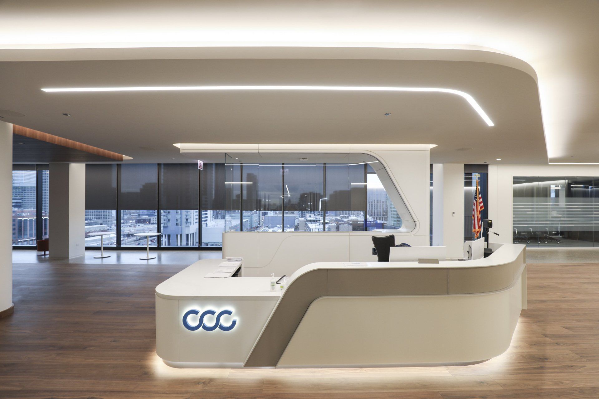 A modern reception desk in a large room with a lot of windows.