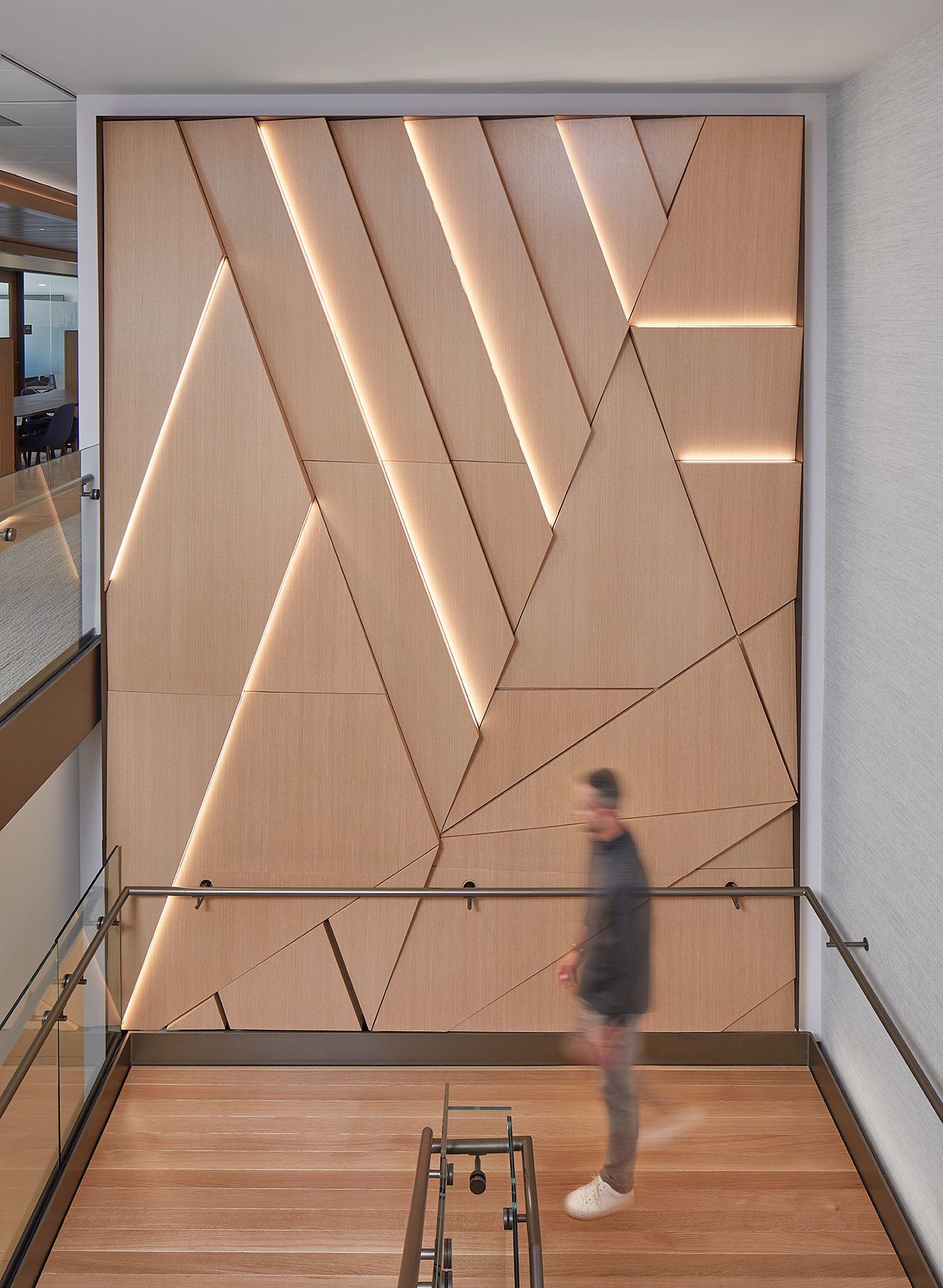 A man is walking down a set of stairs in front of a wooden wall.