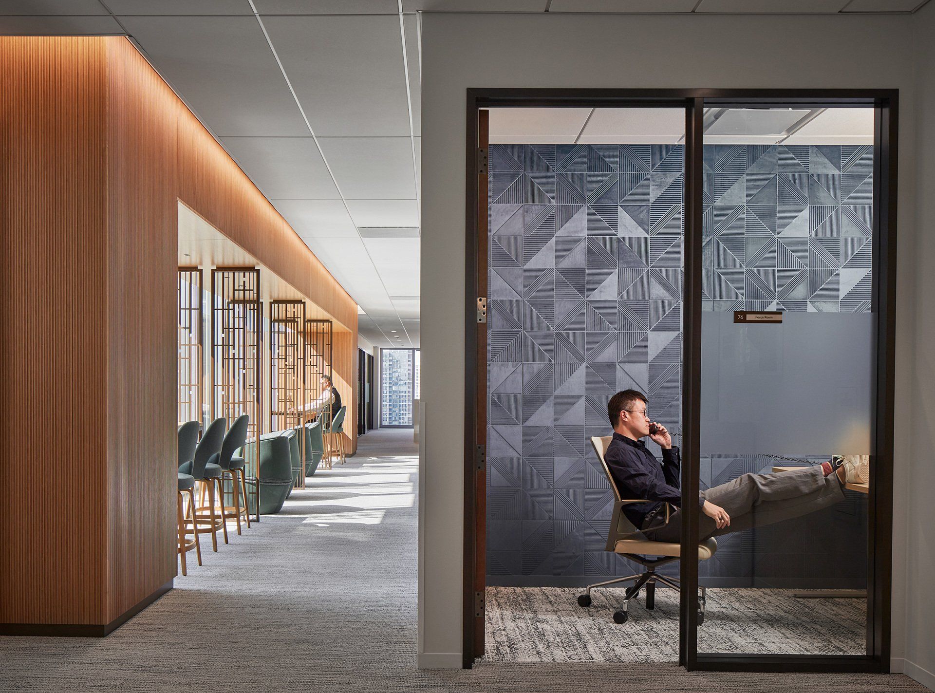 A man is sitting in an office chair talking on a cell phone.