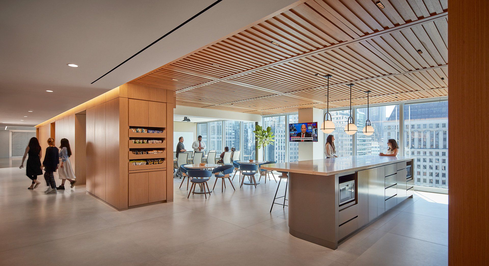 A group of people are walking through a large room with tables and chairs.