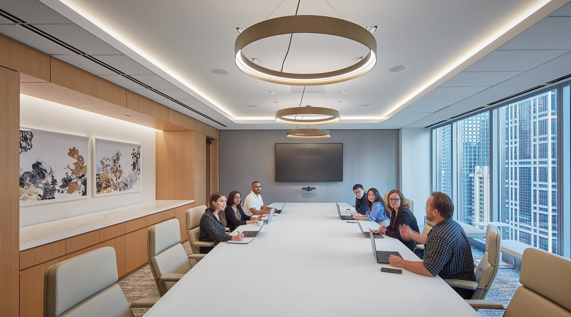 A group of people are sitting around a long table in a conference room.