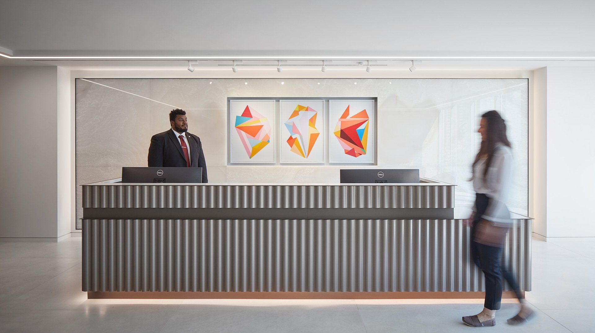 A woman is walking past a reception desk in a hotel lobby.