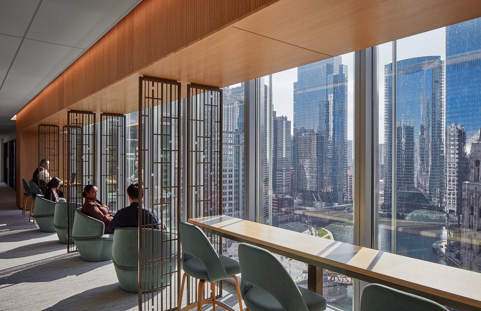 A group of people are sitting in chairs in front of a large window overlooking a city.