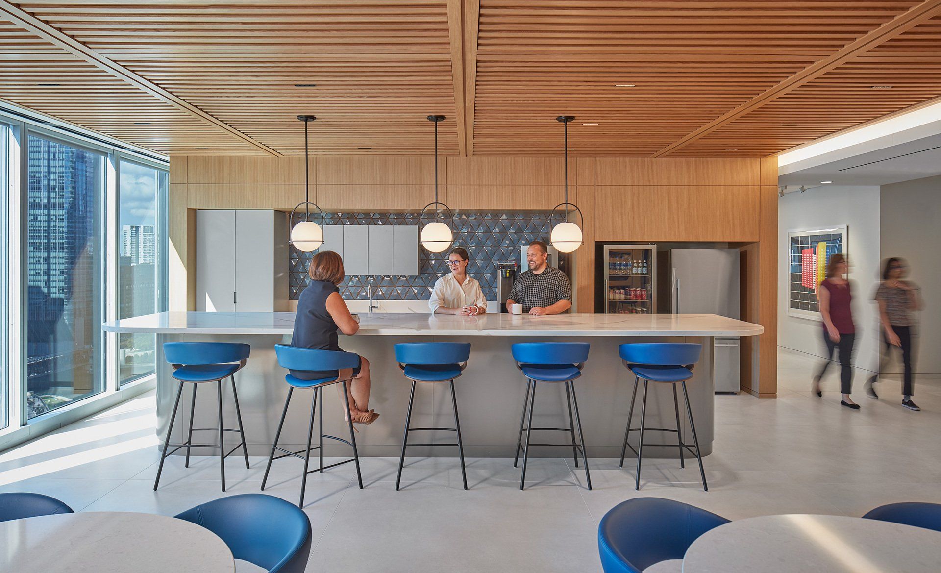 A group of people are sitting at a long counter in a kitchen.