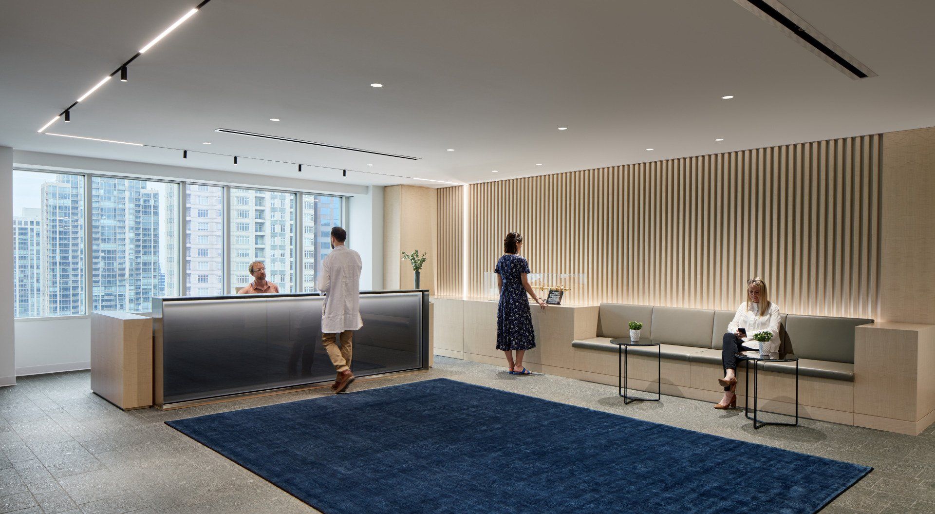 A man and a woman are standing at a reception desk in a lobby.