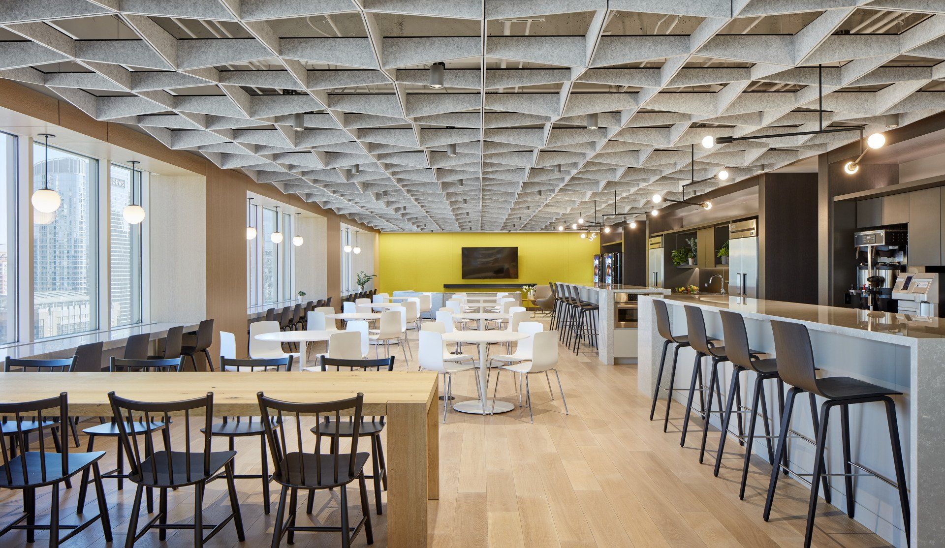 A large dining room with tables and chairs and a yellow wall.