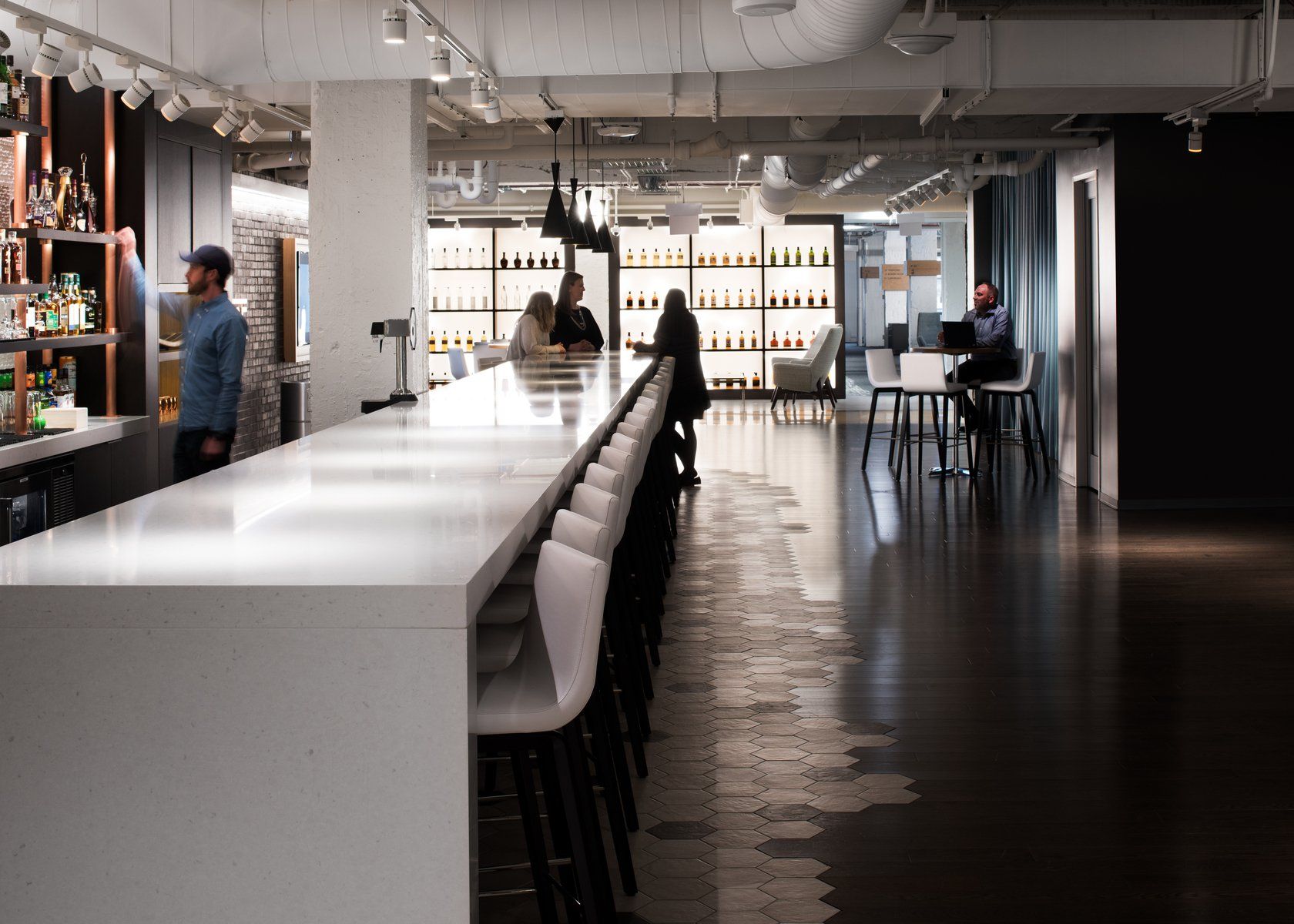 A long white bar in a restaurant with people sitting at tables.