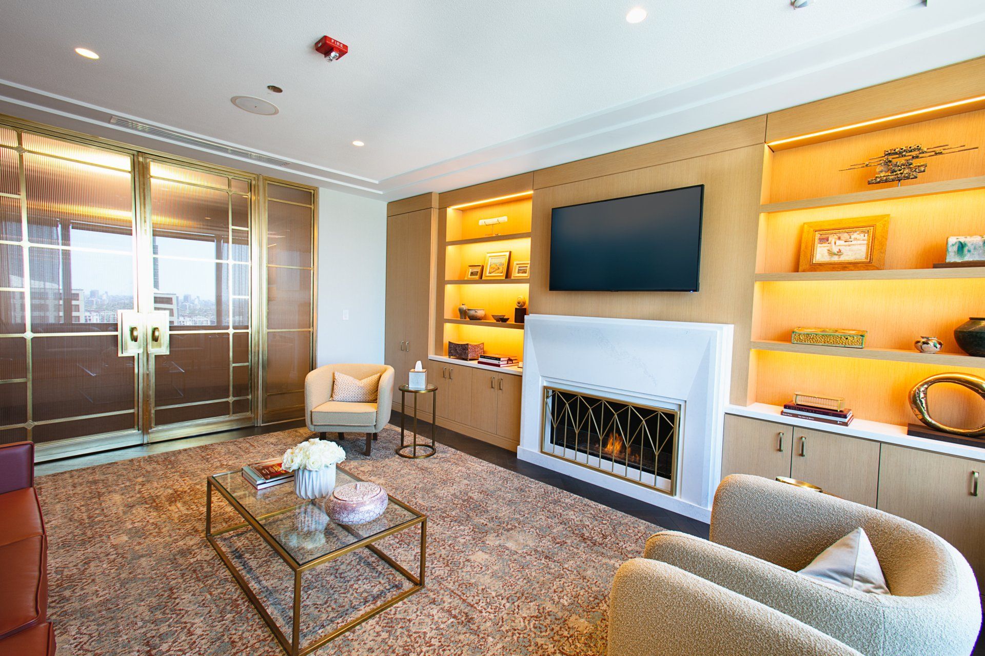 A living room with a fireplace , chairs , a coffee table and a flat screen tv.