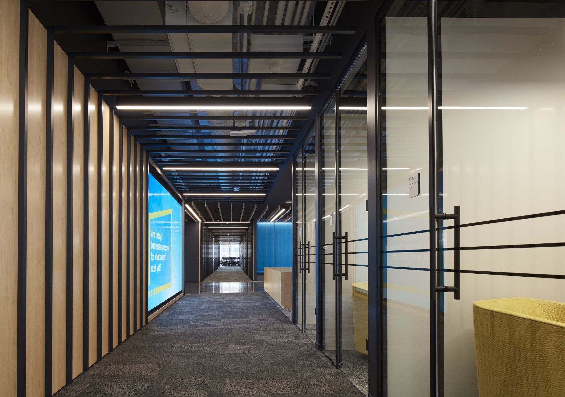 A long hallway with glass doors and a large screen on the wall.