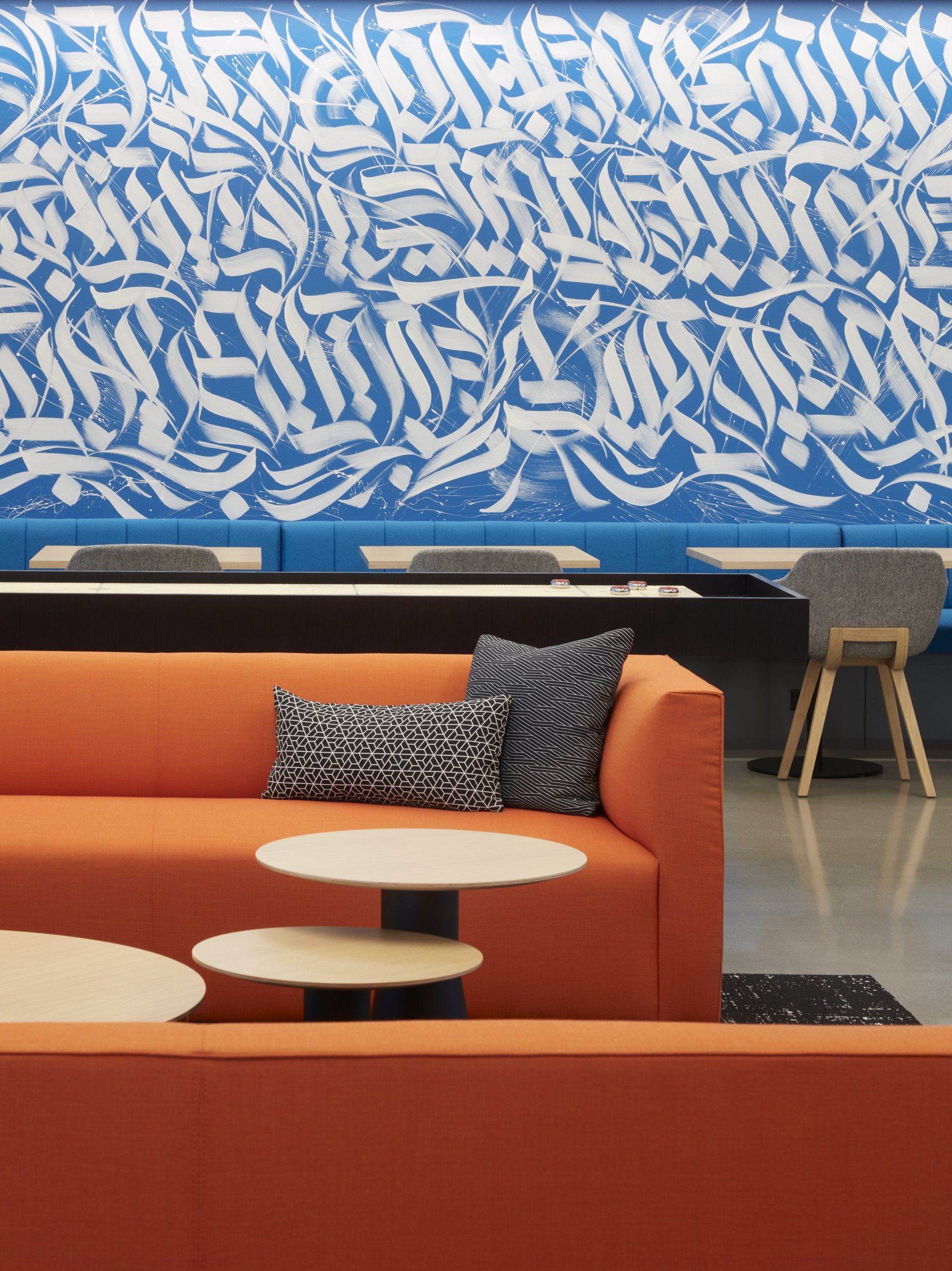 A living room with an orange couch and a blue wall with graffiti on it