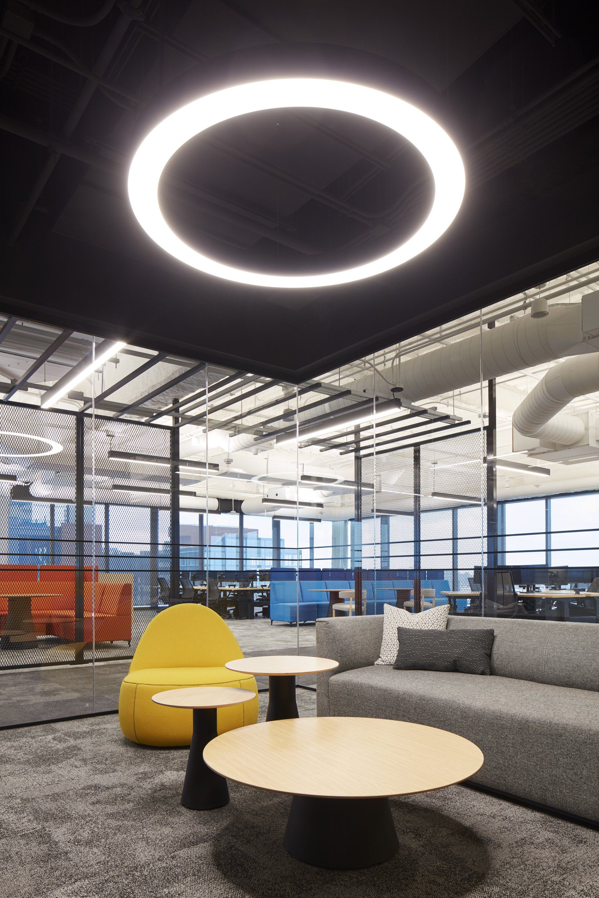 A living room with a circle light hanging from the ceiling.