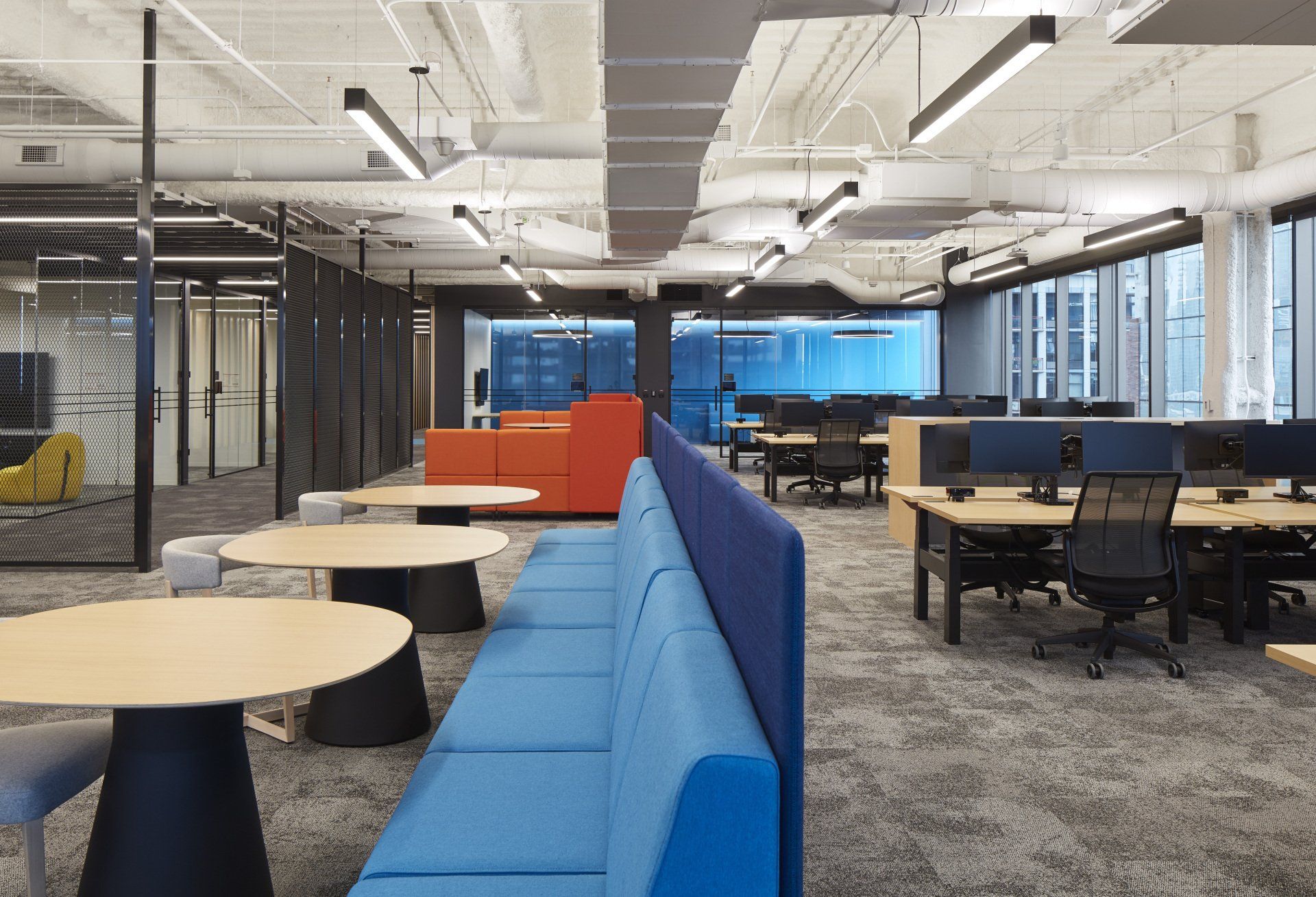 A large office with tables and chairs and a blue couch.