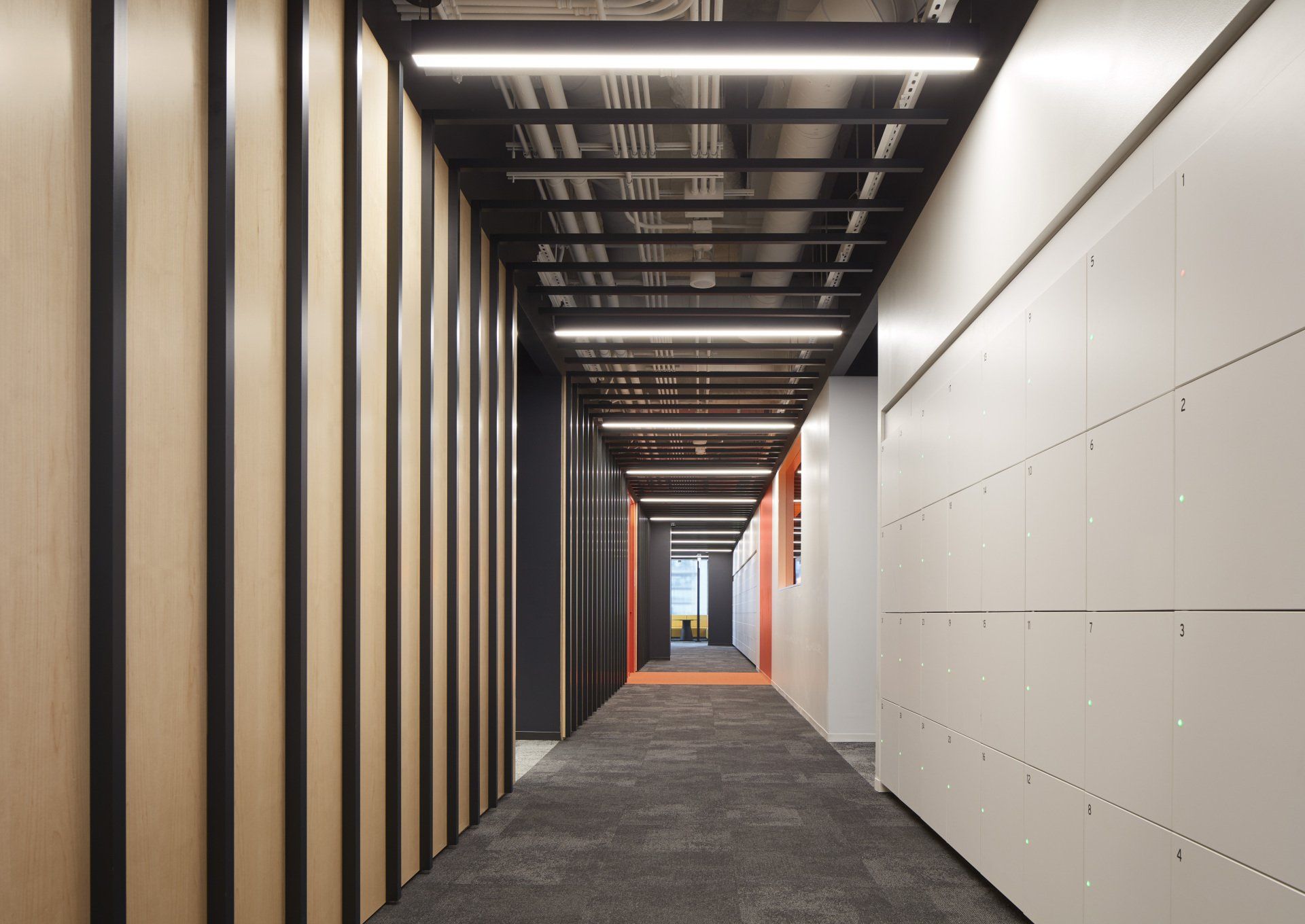 A long hallway with wooden walls and a carpeted floor in an office building.