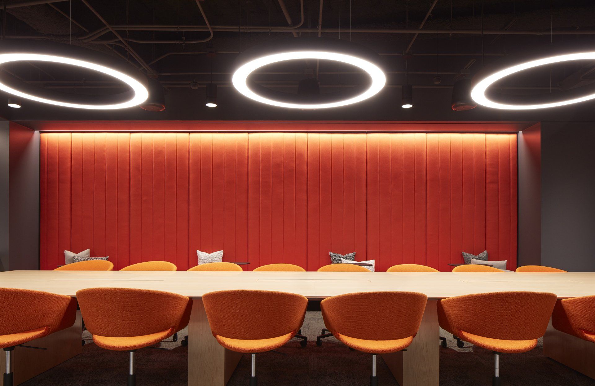A conference room with a long table and orange chairs.