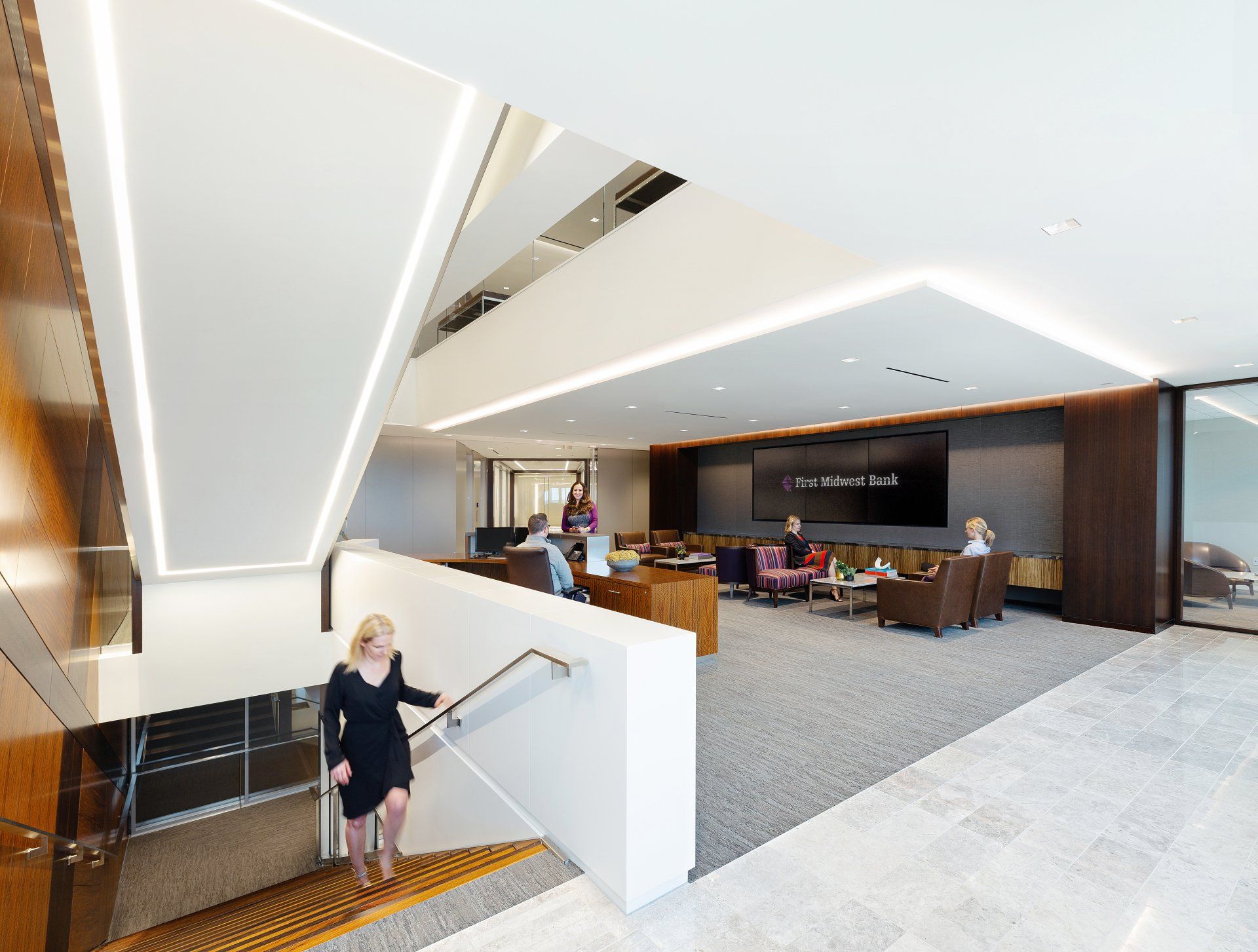 A woman is walking down a set of stairs in an office building.