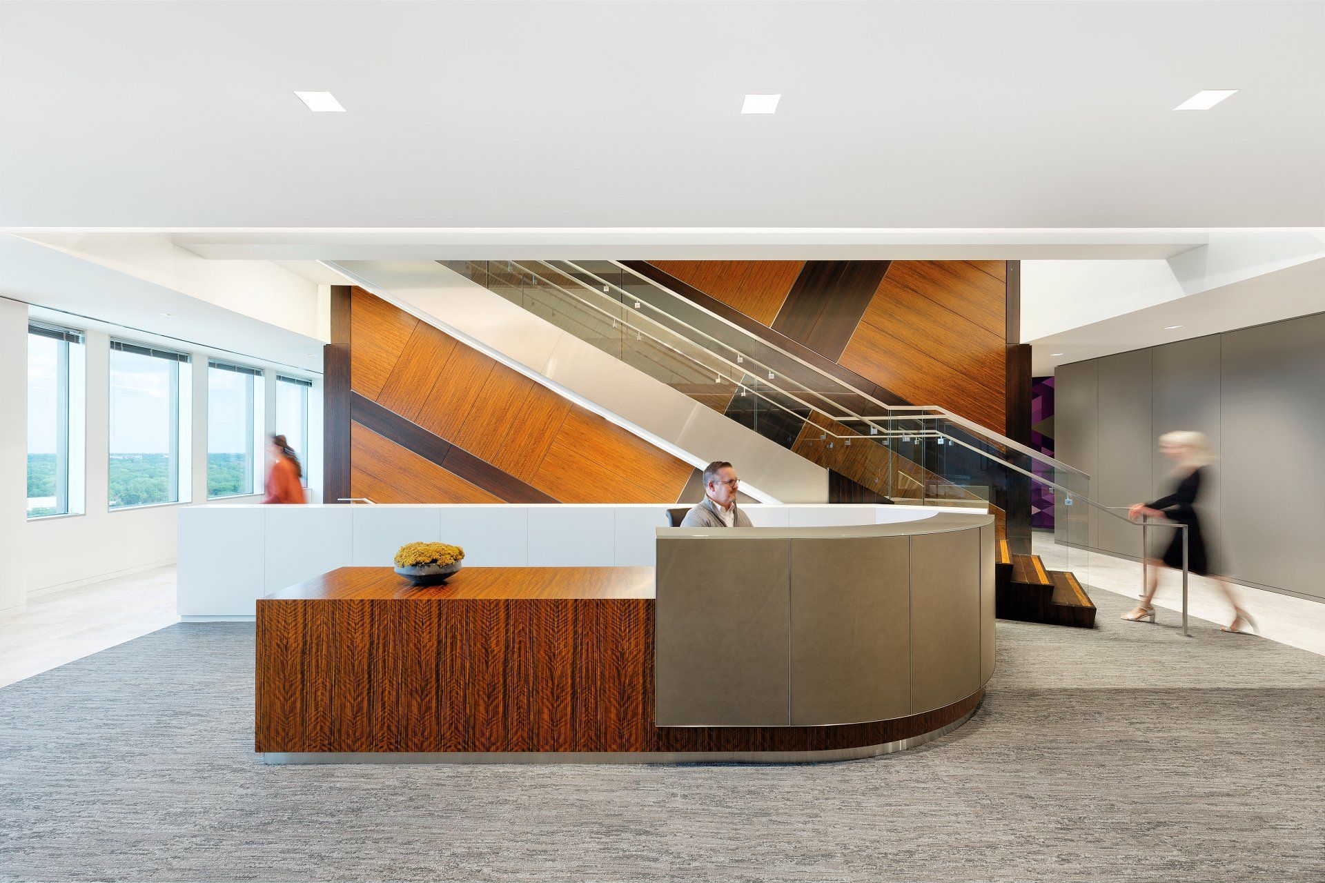 A woman is walking past a reception desk in an office building.