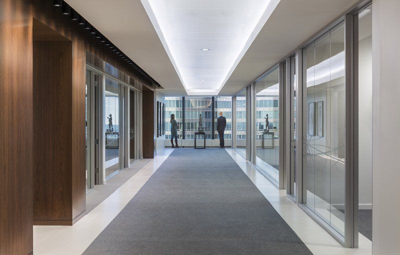 A long hallway in an office building with people walking down it.