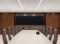 A conference room with a long table and chairs and a large screen.