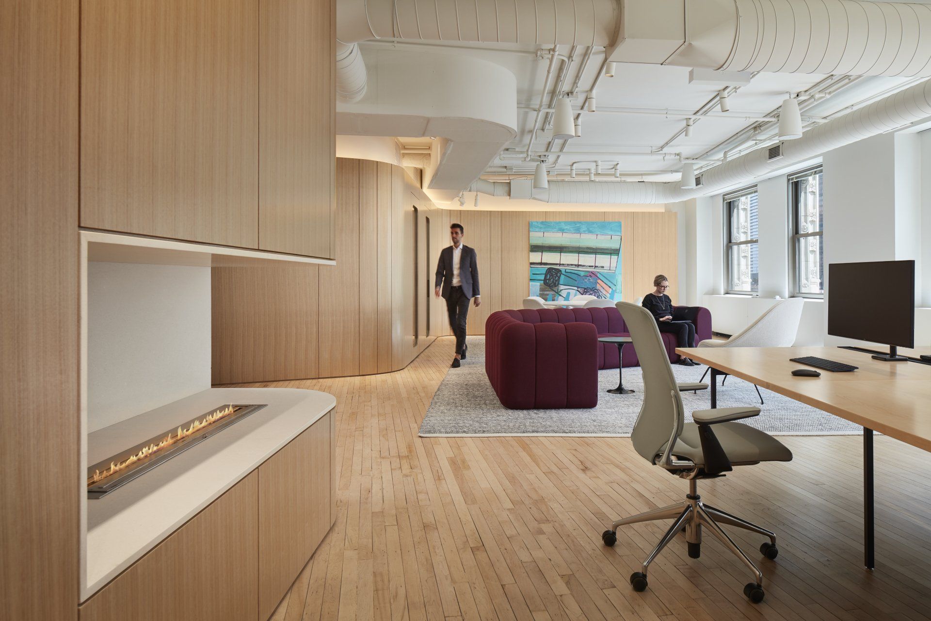 A man is walking through an office with a fireplace.