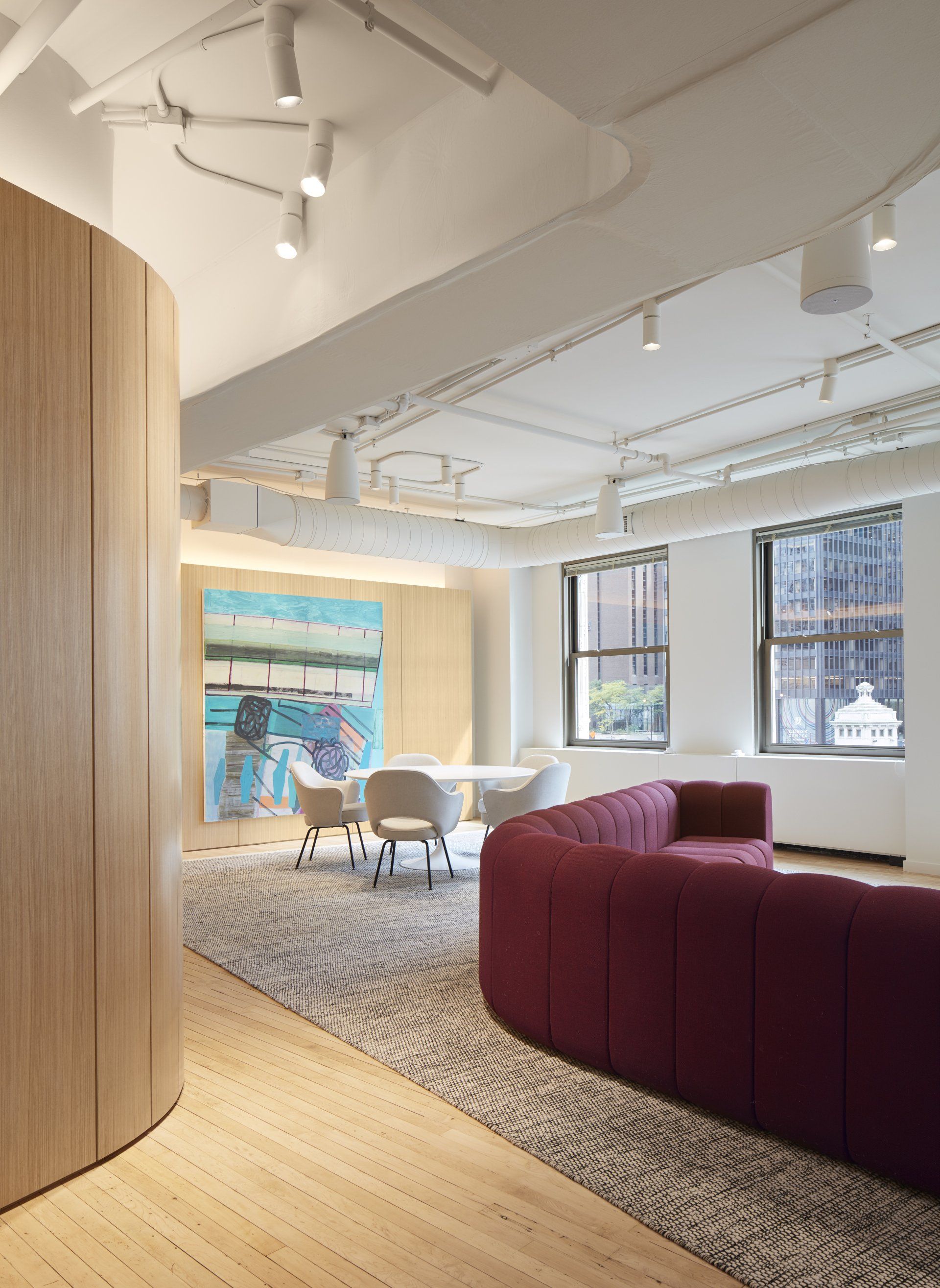 A living room with a couch , chairs , a table and a painting on the wall.