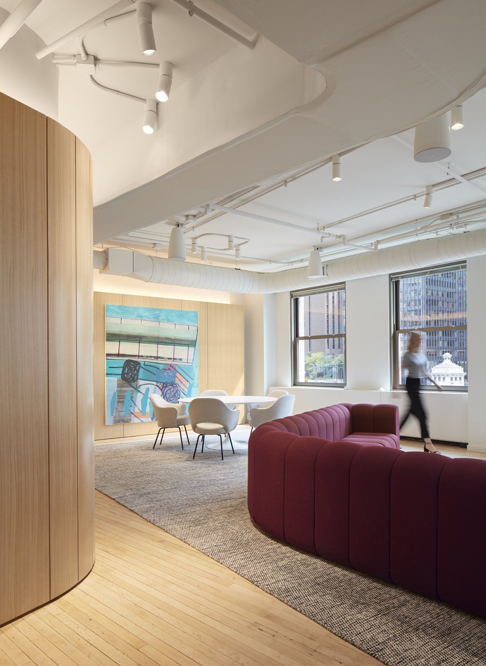 A woman is walking through a room with a couch and chairs.