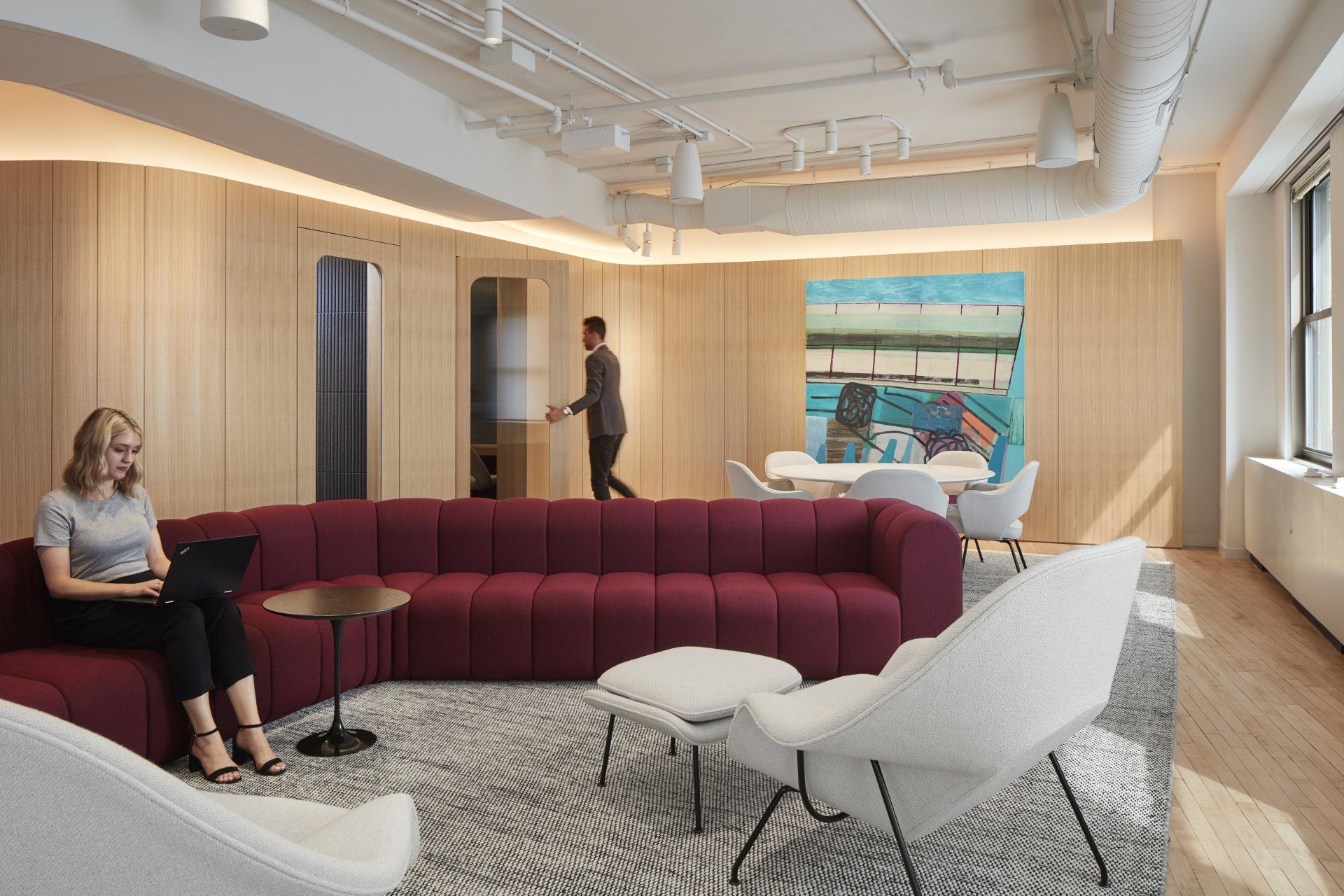 A woman is sitting on a couch in a living room with a laptop.