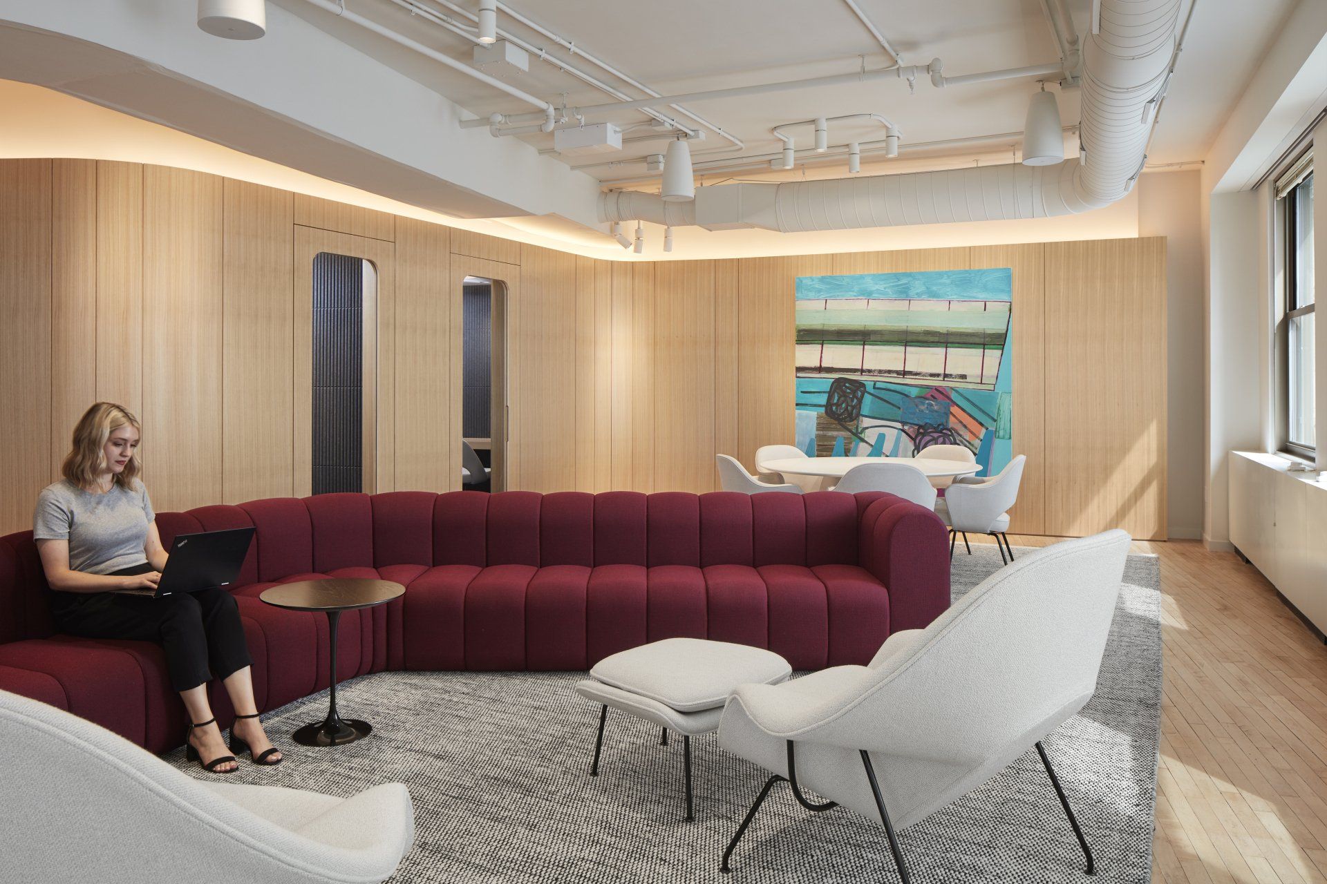 A woman is sitting on a couch in a living room with a laptop.