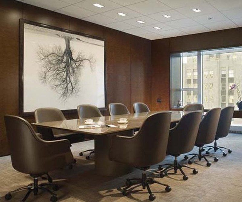 A conference room with a table and chairs and a painting of a tree on the wall.