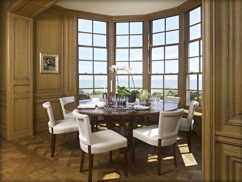 A dining room with a round table and white chairs