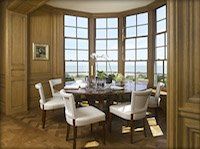 A dining room with a table and chairs and a lot of windows.