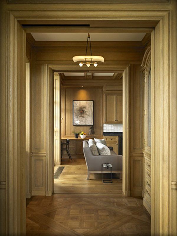 A hallway leading to a living room with a couch and a desk