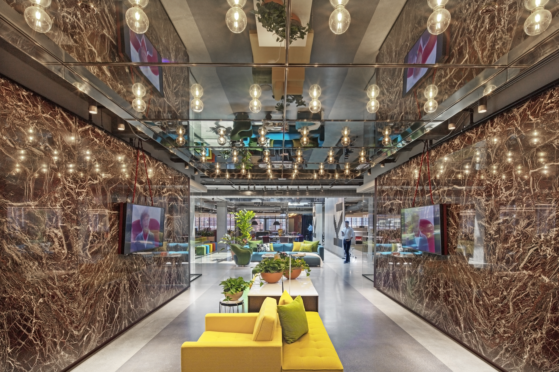 A lobby with a yellow couch and a mirrored ceiling