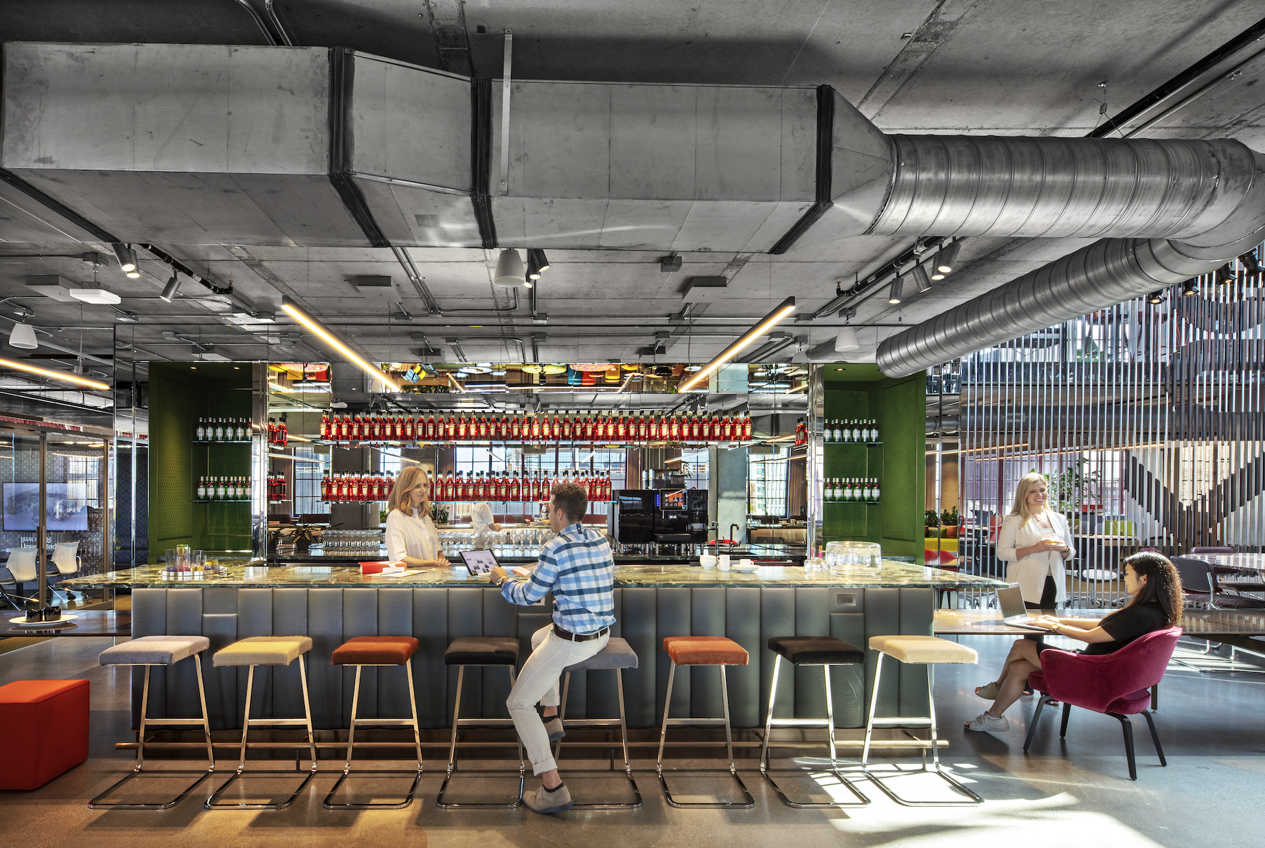 A man is sitting on a bar stool in a restaurant.