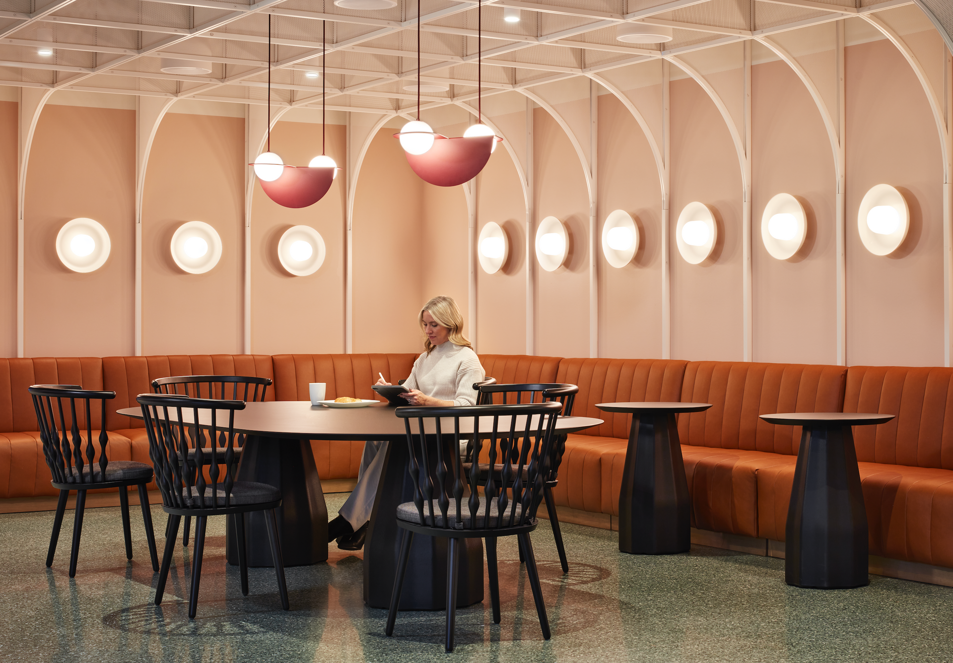 A woman is sitting at a table in a restaurant reading a book.