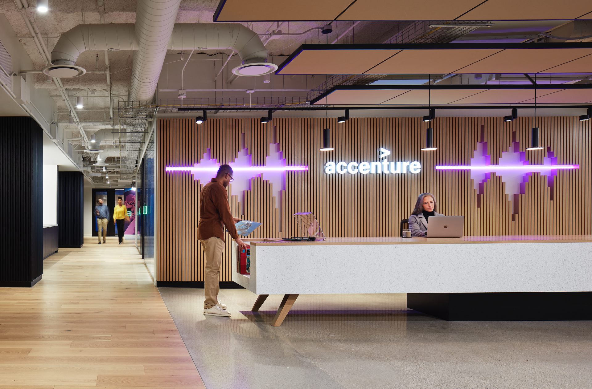 A man is standing in front of a reception desk in an office building.