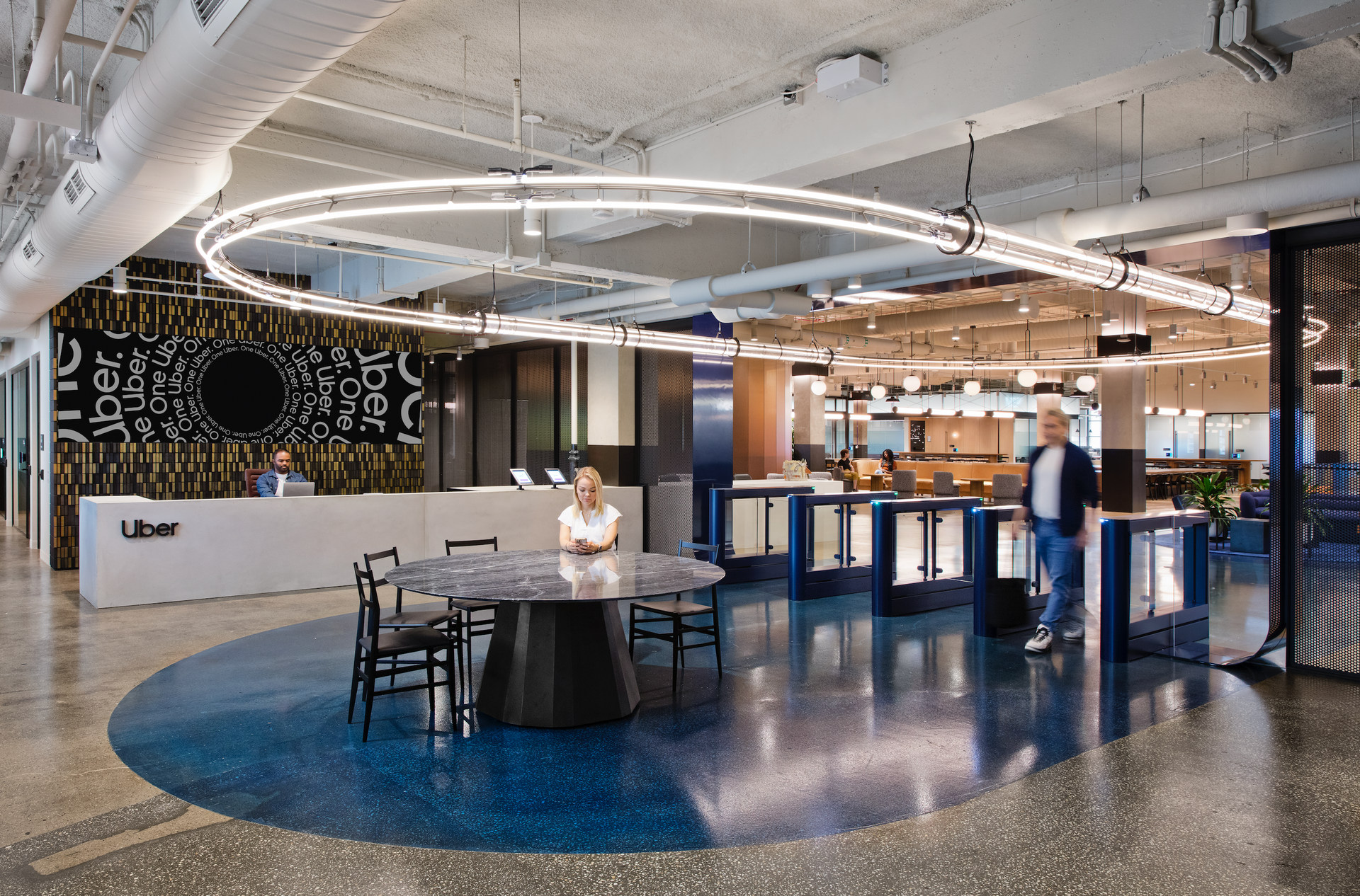 A woman is sitting at a table in a lobby of an office building.