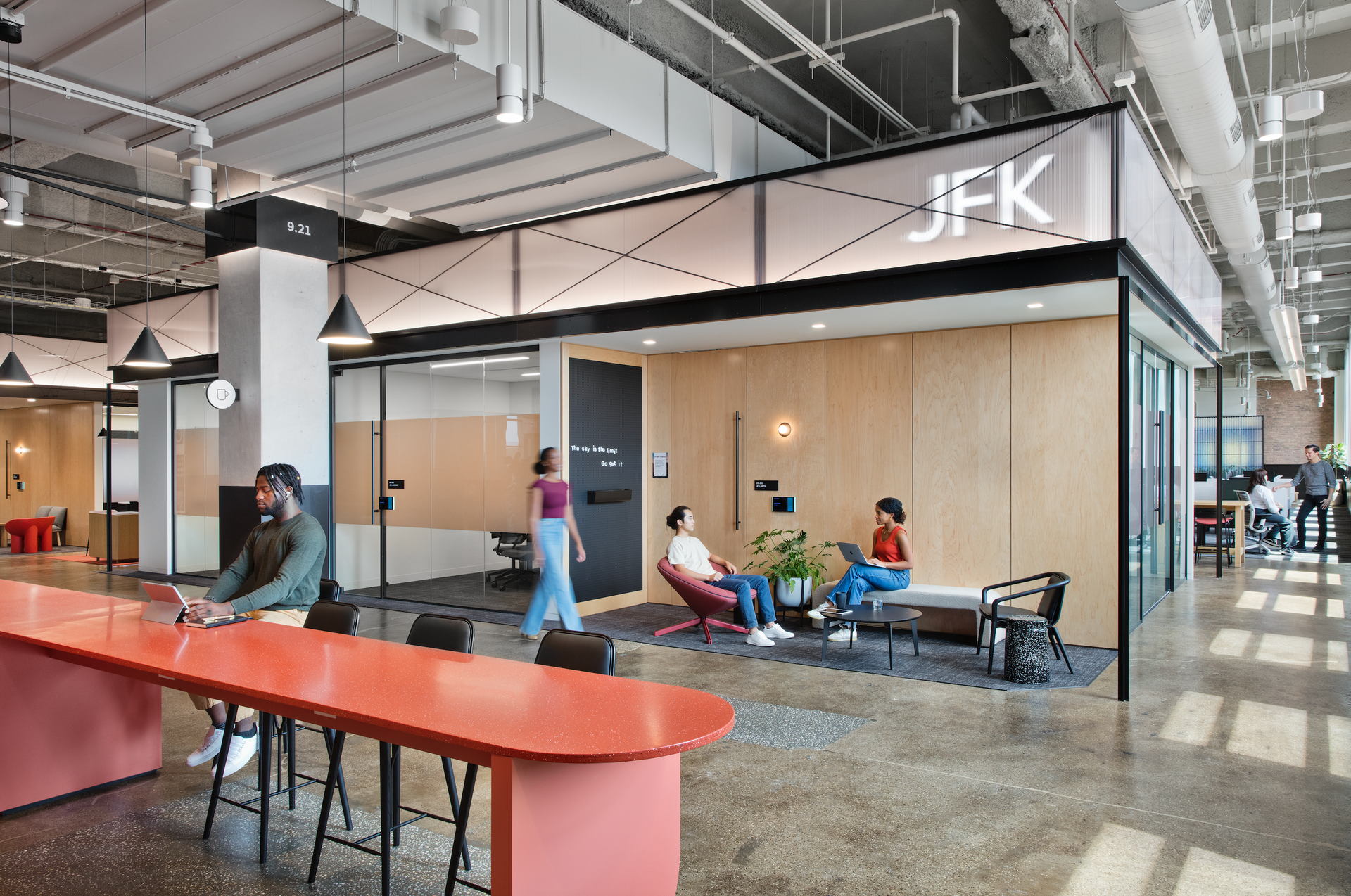 A group of people are sitting at a long table in a large room.