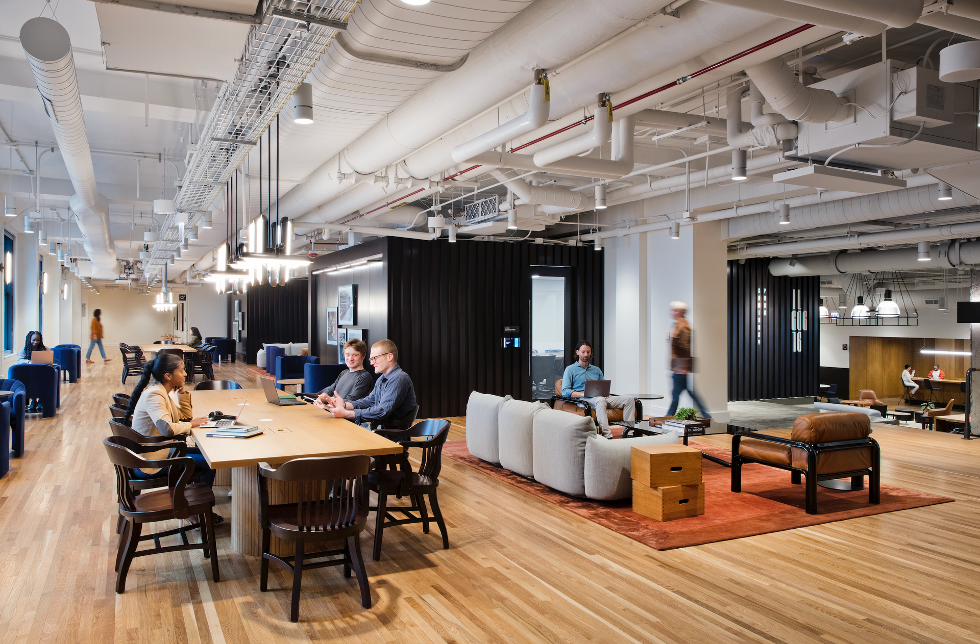 A group of people are sitting at a table in a large room.