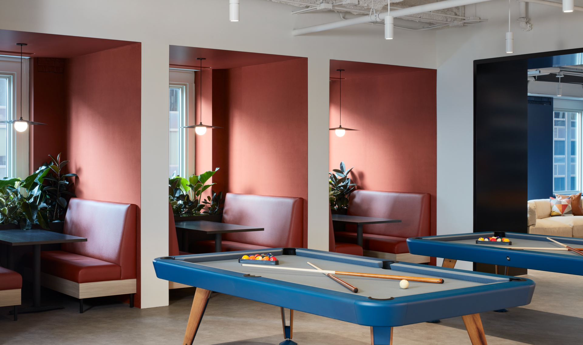 A pool table in a room with tables and benches.