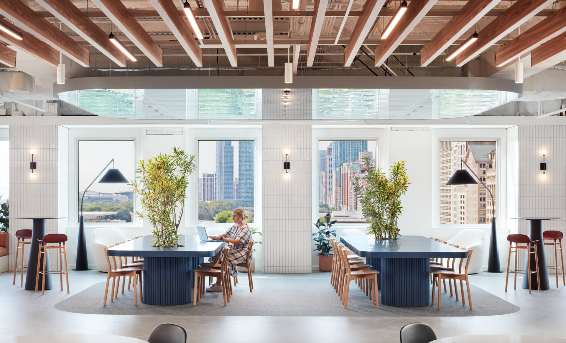 A woman is sitting at a long table in a large room.