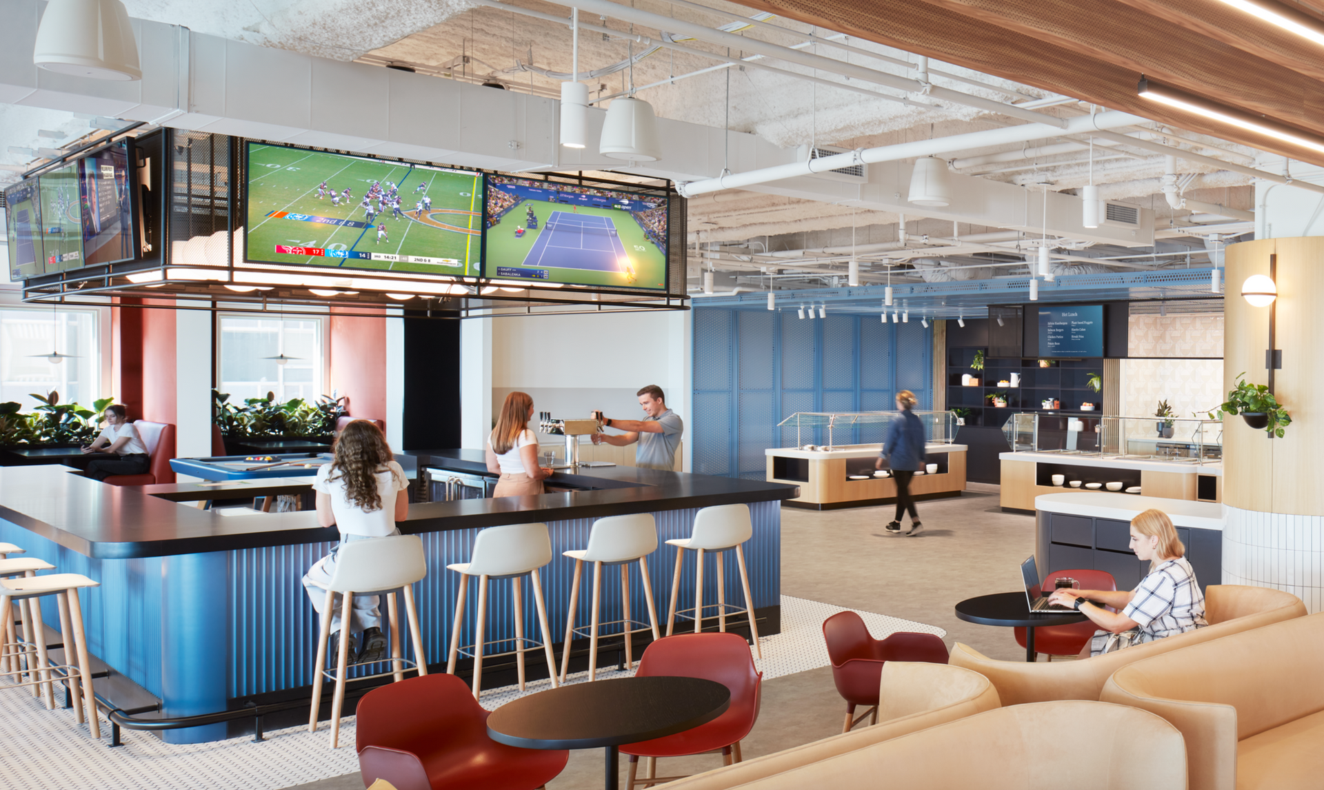 A group of people are sitting at a bar in a large room.