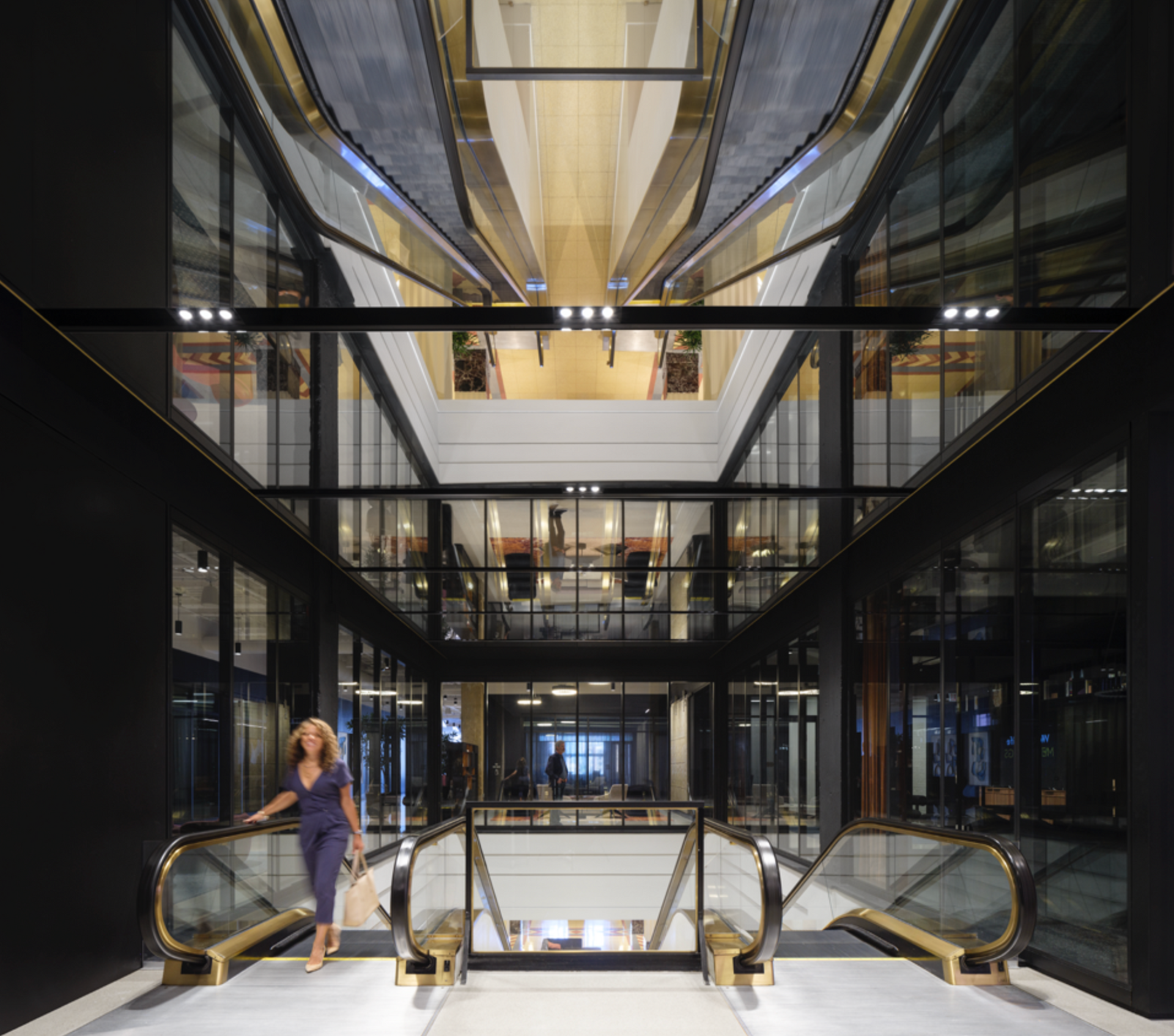 A woman is walking down an escalator in a building