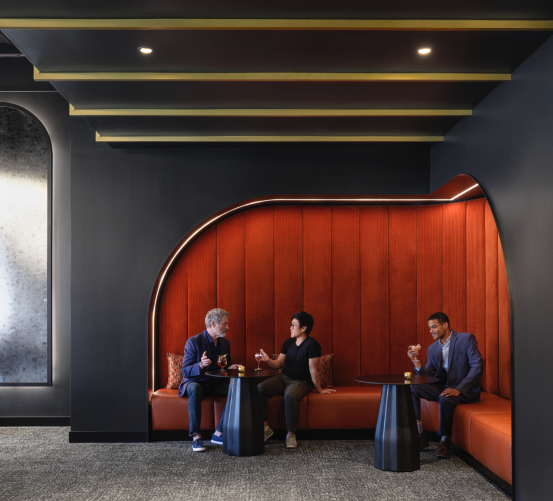 Three men are sitting on a couch in a room talking to each other.