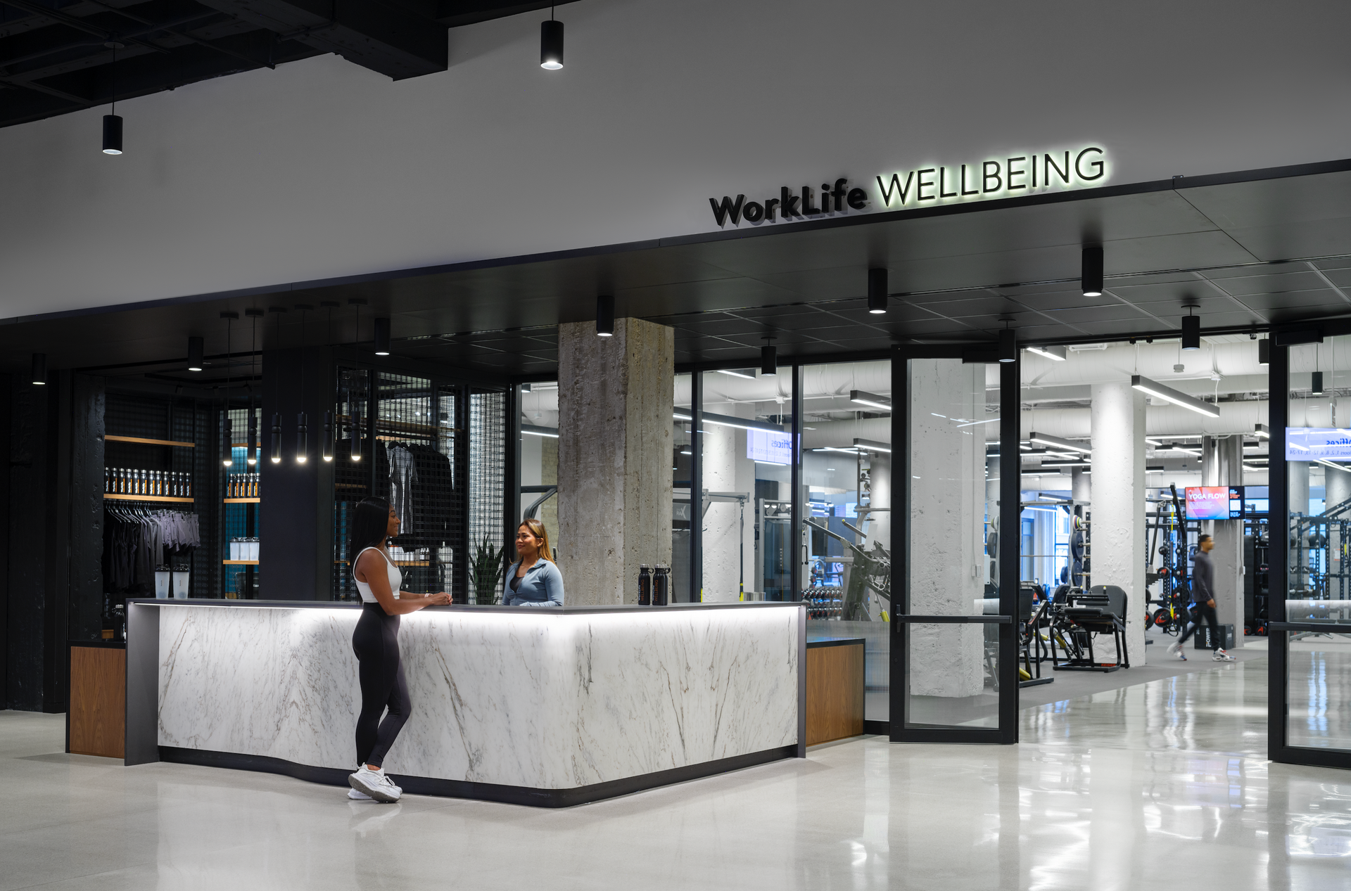A woman is standing at a counter in front of a gym.