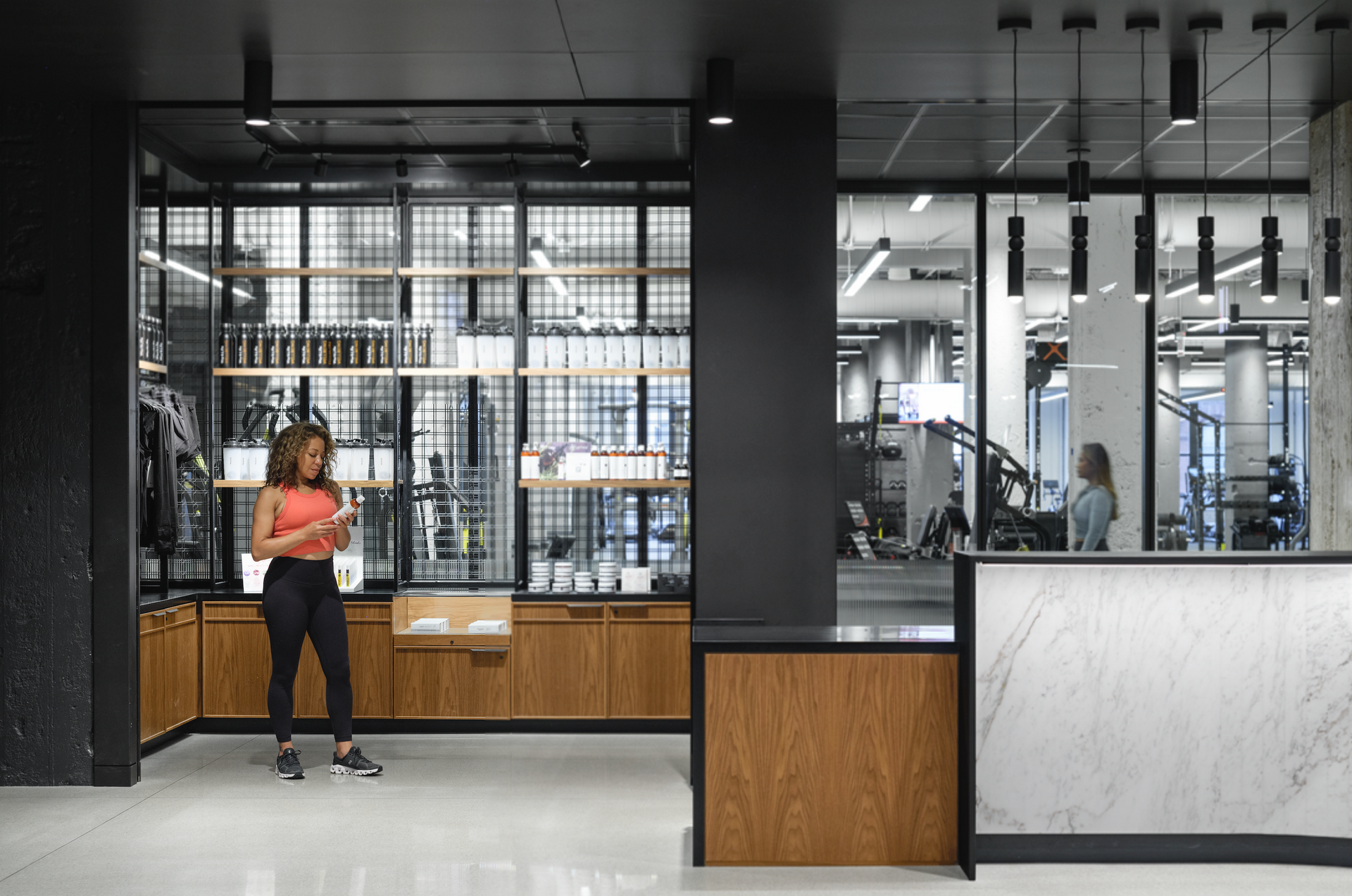 A woman is standing in a room looking at her phone.