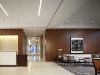 A lobby with a couch , chairs , tables and a painting on the wall.