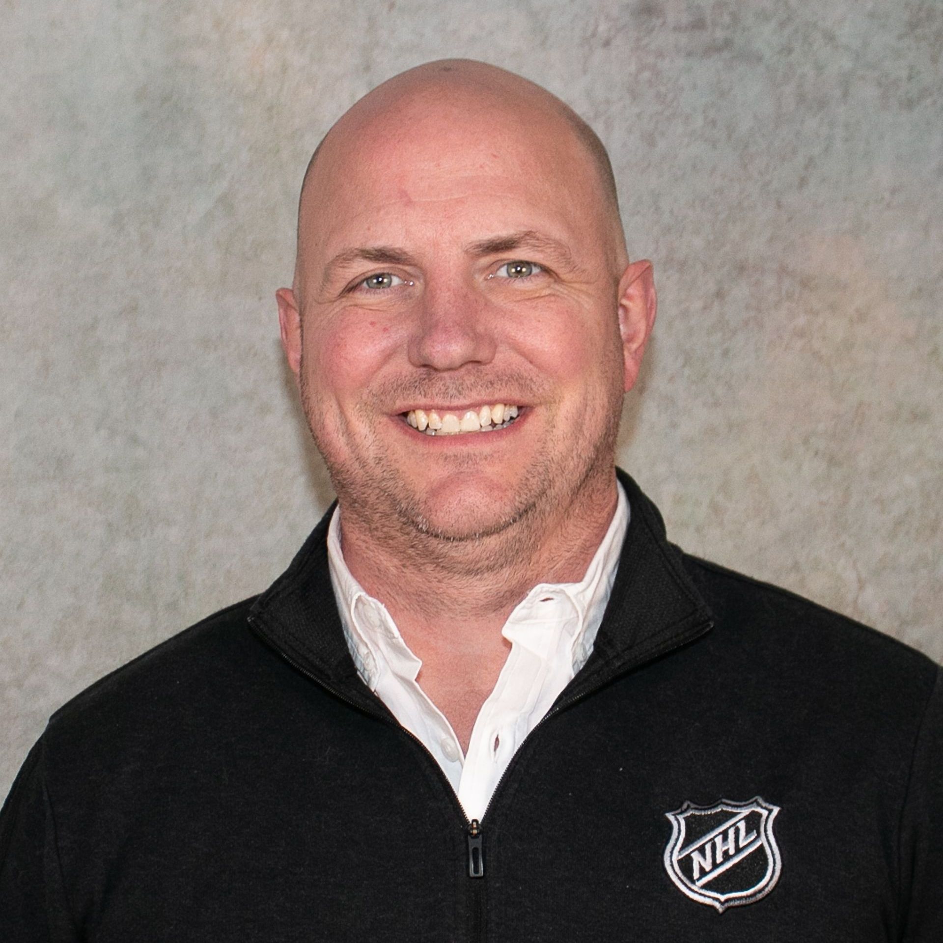 A man in a suit and white shirt is smiling for the camera.
