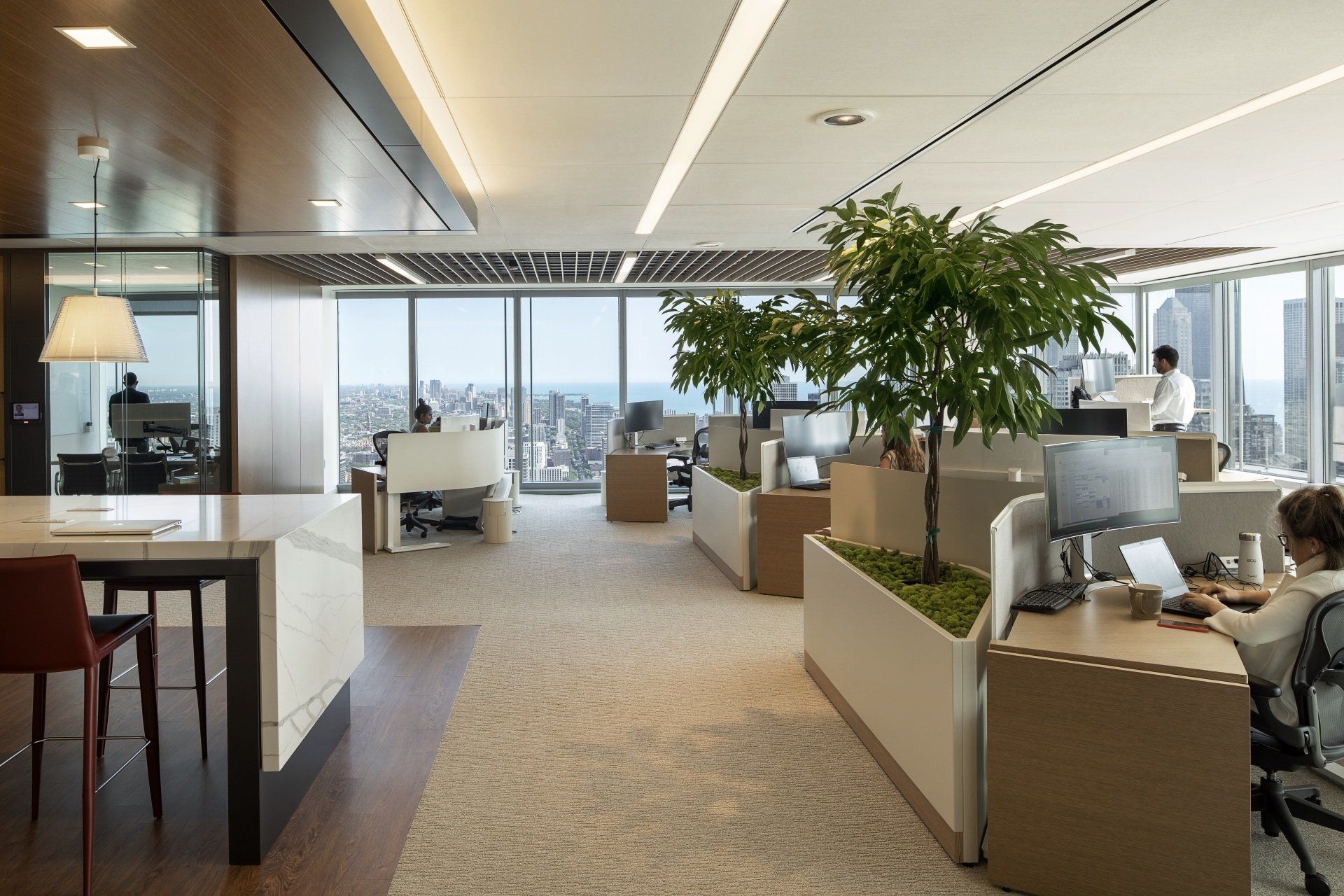 A man is sitting at a desk in an office with a view of the city.