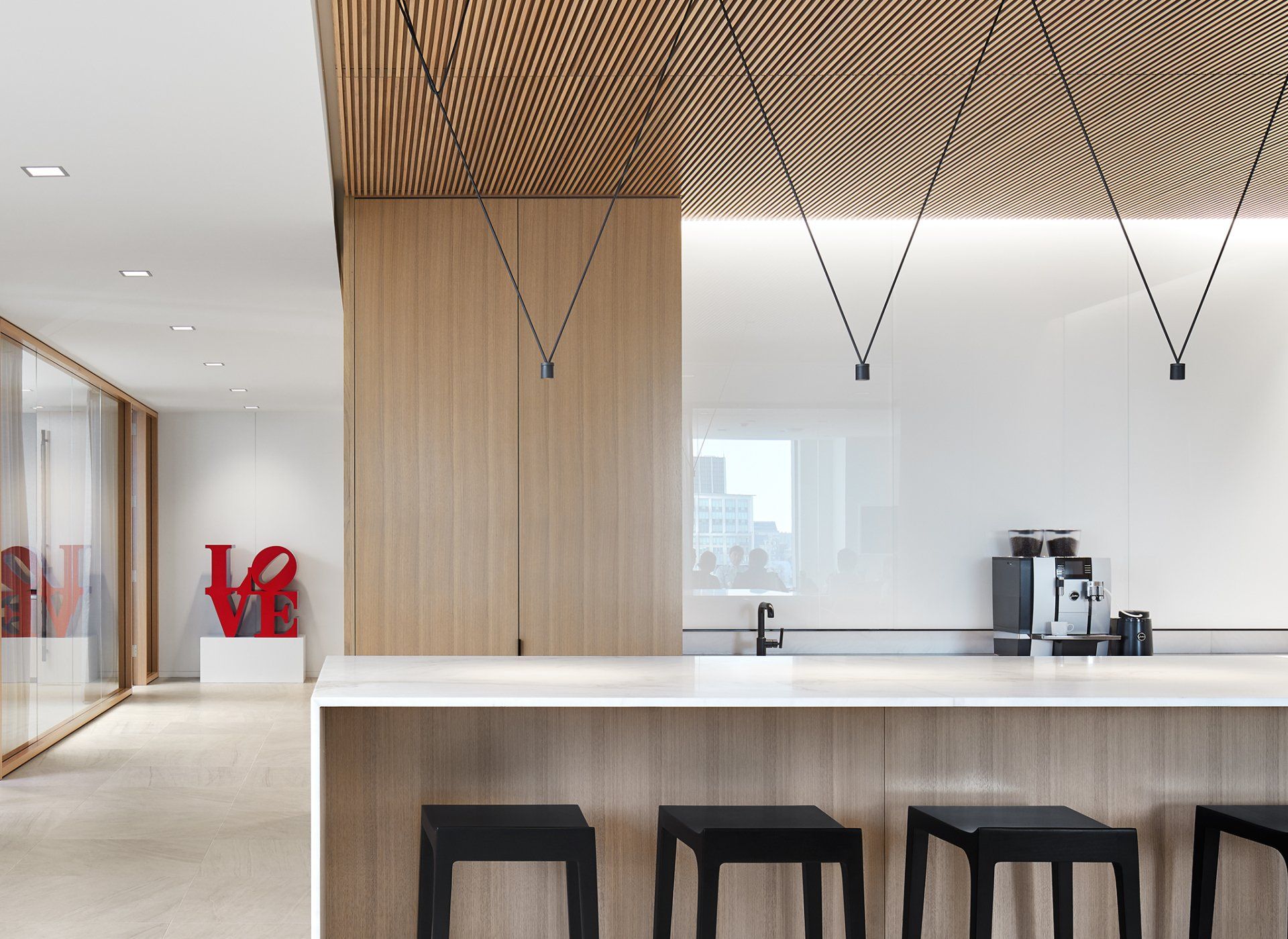 A kitchen with a bar and stools and a love sign on the wall.
