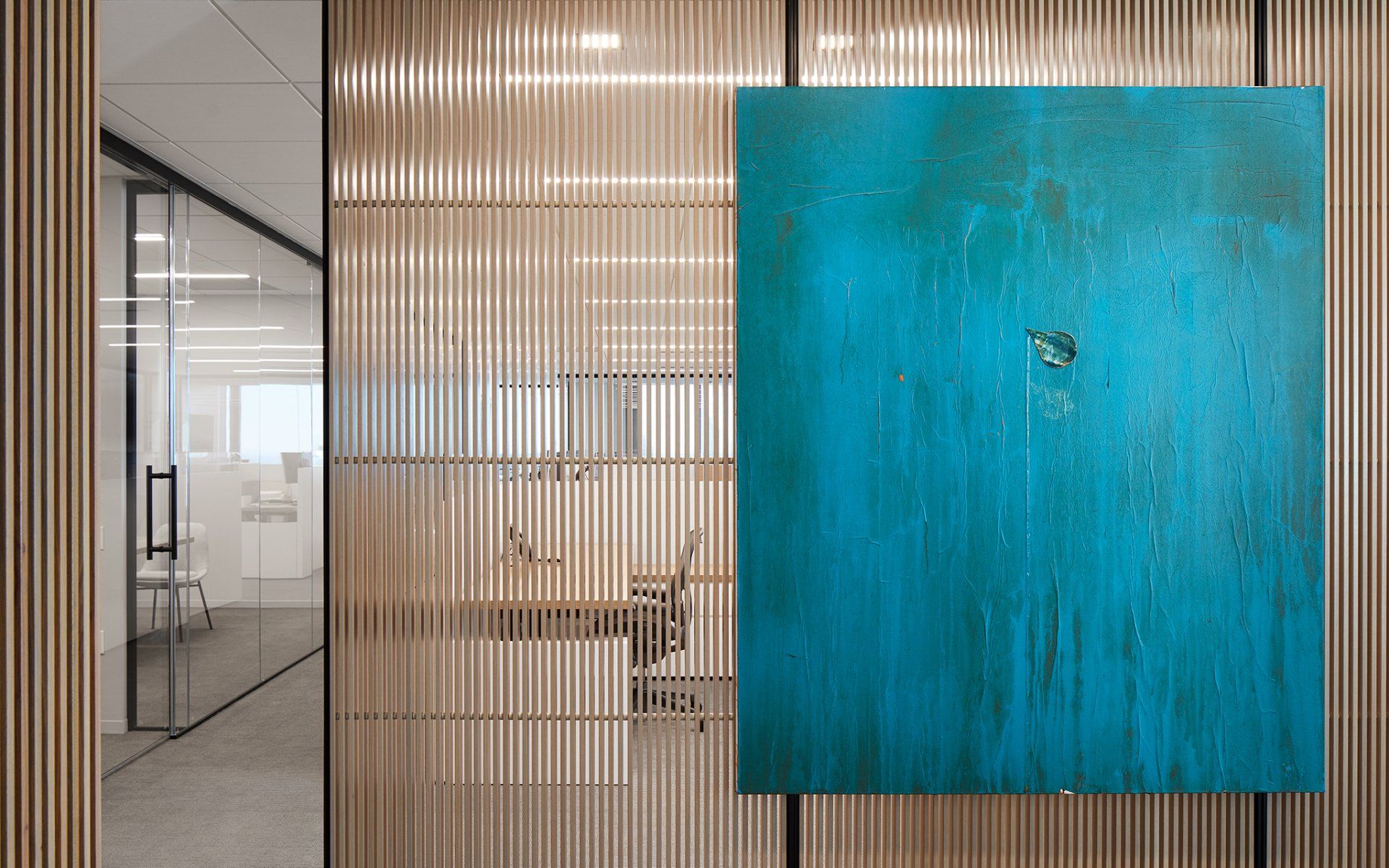 A large blue painting is hanging on a wooden wall in an office.